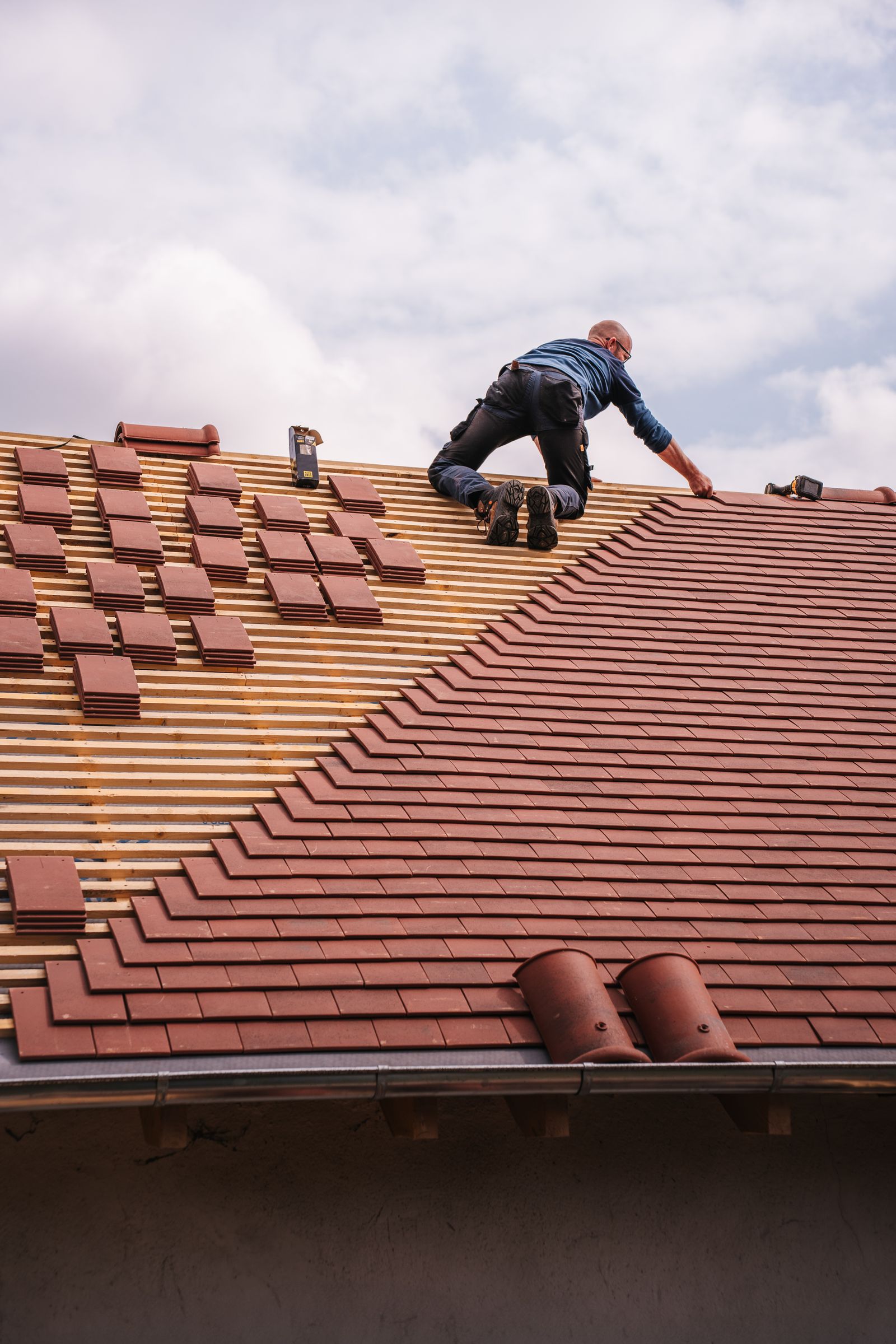 Professional roofer installing roof tiles during a fall roof inspection — Asscher Roofing